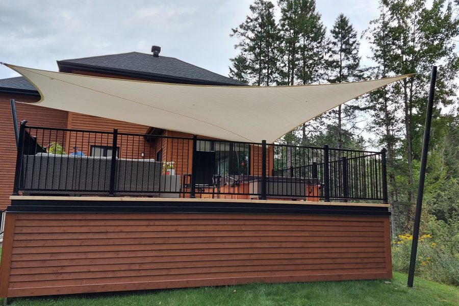 Beige shade sail shading a backyard patio and dining set in an Ontario home